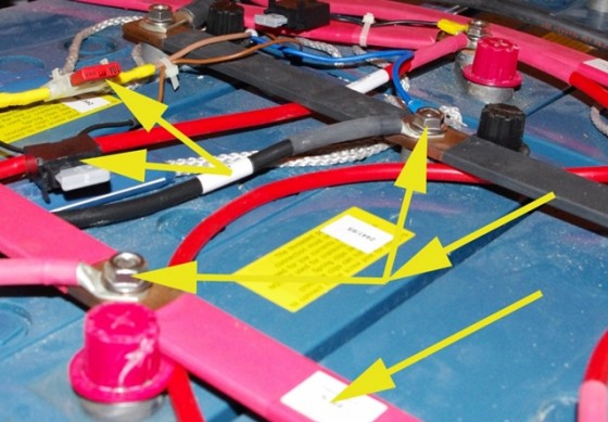 Yellow arrows point to areas of concern in this battery installation.
