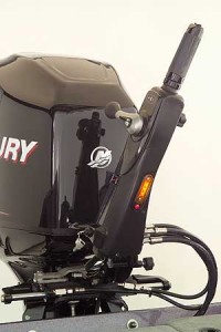 The Mercury Big Tiller with power assist locates a hydraulic valve manifold with the tiller handle. Two hydraulic lines carry fluid to and from an electric pump mounted under the aft deck, while two other lines feed the hydraulic steering ram on the motor bracket. An amber light on the underside of the tiller illuminates the area around the motor at night.