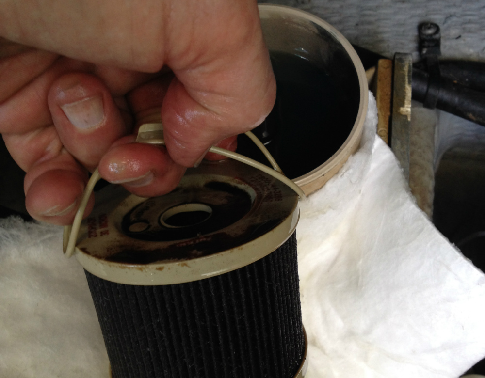 A foul 30-micron element emerges from a Racor fuel filter. Note the almost black color of the fuel in the bowl. The microorganisms have been hard at work in this fuel system.