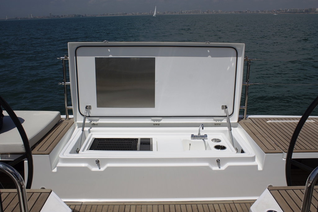 The entire teak-topped transom is a sunpad that hides a galley module below. An electrically raised grill, sink, and prep station pop out of the transom, and a 42-quart mini-fridge is at cockpit sole height next to the port wheel. 